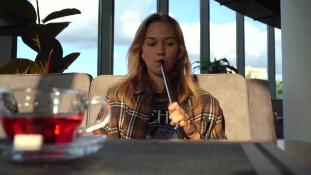 Ένα κορίτσι καπνίζει ναργιλέ σε ένα εστιατόριο. — Αρχείο Βίντεο