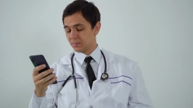 Doktor ofiste otururken telefonu kullanıyor.