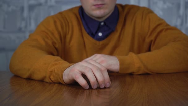 Un hombre sentado en la mesa golpea sus dedos sobre la mesa debido al estrés — Vídeos de Stock