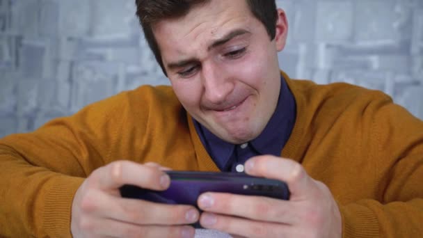 Man die aan de telefoon speelt terwijl hij aan tafel zit — Stockvideo