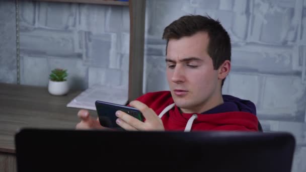 Чоловік використовує телефон, сидячи в ноутбуці — стокове відео