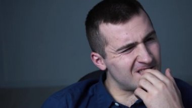 Gömlekli bir adam tırnaklarını yiyor.