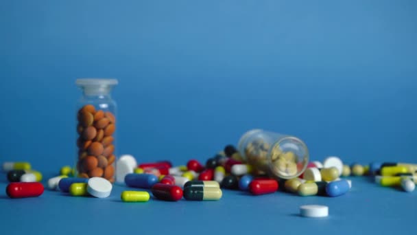 Ein Haufen Pillen, chaotisch auf blauem Hintergrund verstreut — Stockvideo