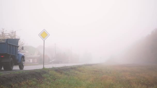 Los coches conducen a lo largo de la carretera cubierta de niebla gruesa — Vídeos de Stock