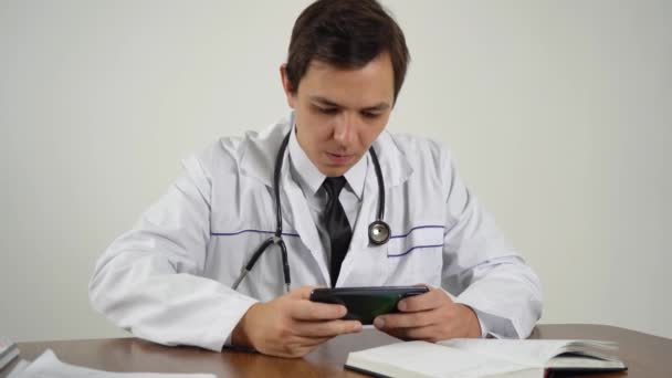 Läkaren spelar telefonen på arbetsplatsen — Stockvideo