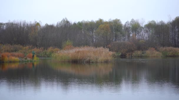 A man fishing on the river bank in the autumn — Stock Video