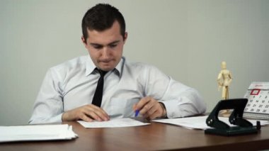 Bir adam ofisinde otururken belgelere bakar.
