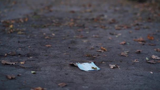 Máscara encontra-se no asfalto no parque em clima de outono — Vídeo de Stock