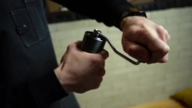 Barista kahve çekirdeklerini öğütmek için elle kahve öğütücü kullanıyor.