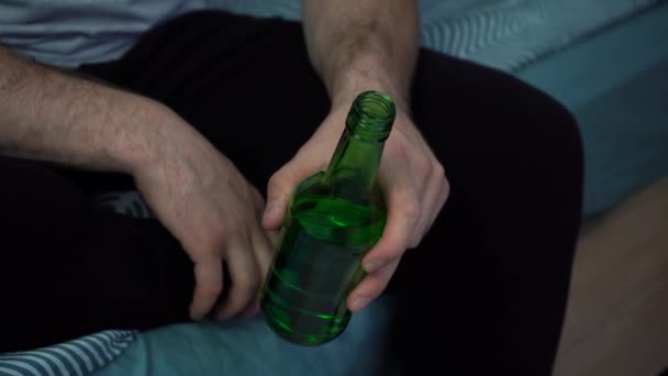 Man dricka öl från glas grön flaska medan du sitter på soffan — Stockvideo