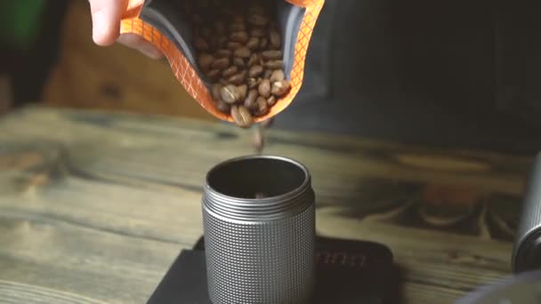 Мужчина наливает кофейную фасоль в ручную кофейную терку — стоковое видео