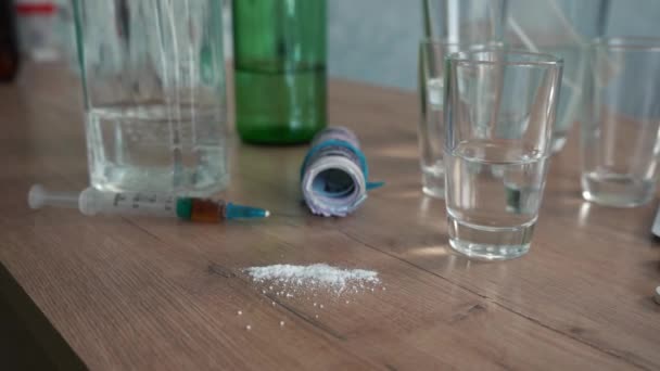 Hombre pone un puñado de pastillas sobre la mesa con alcohol y drogas — Vídeos de Stock