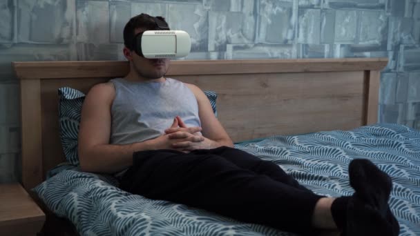 VR gözlüklü bir adam kanepede uzanmış film izliyor. — Stok video