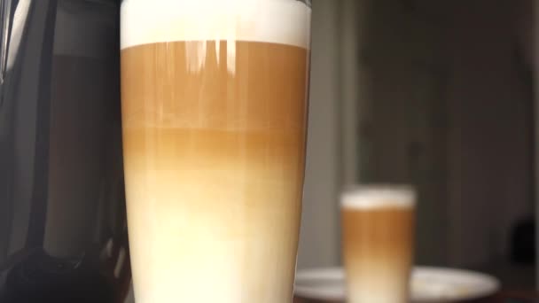 Latte em um copo de vidro está na mesa — Vídeo de Stock