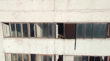 Kırık camlı terk edilmiş bir fabrikanın duvarları boyunca kameranın dikey hareketi.