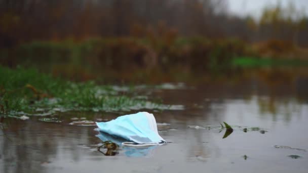 Masker drijft langzaam de rivier af. milieuverontreinigingsconcept — Stockvideo