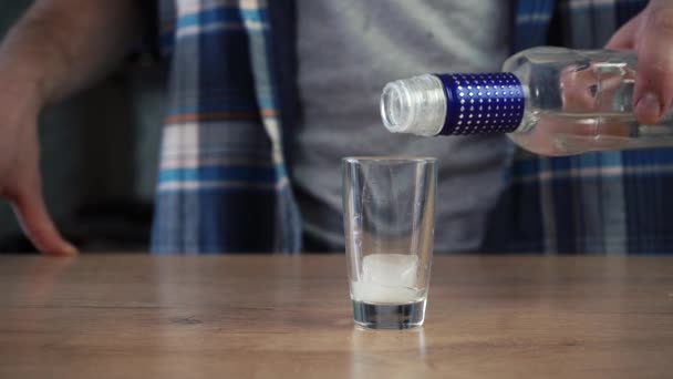 Een man schenkt wodka en glazen met ijs en drinkt het — Stockvideo