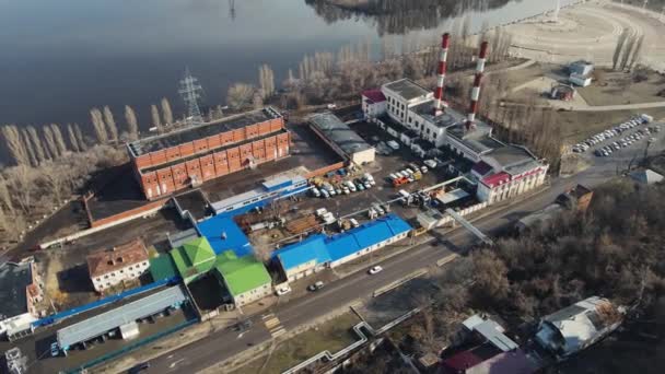 Budynek przemysłowy z drogą i rurami nad rzeką. zdjęcia lotnicze — Wideo stockowe