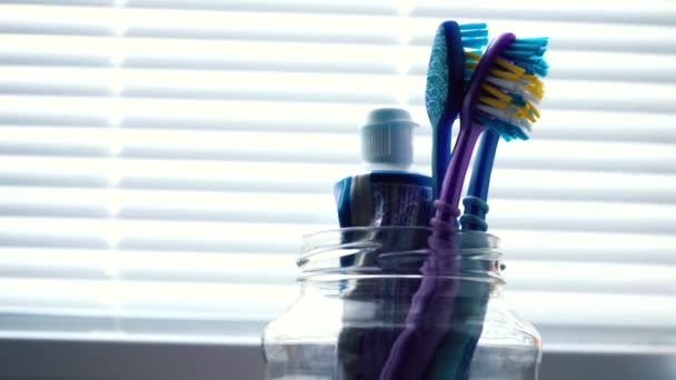 Toothbrushes are placed in a glass intended for brushes — Stock Video