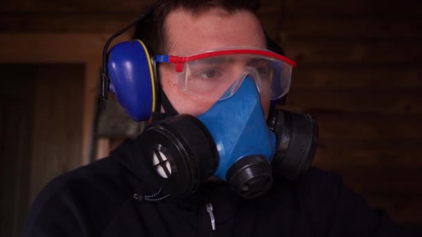 Man works in a respirator, goggles and earmuffs to protect eyesight, breathing — Stock Video