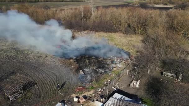 Afval verbranden in de buurt van het huis in een groot gebied. Schieten vanuit de lucht — Stockvideo