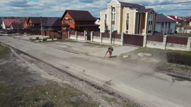 Um homem limpando a estrada com um dispositivo especial para colocar novo asfalto. antena — Vídeo de Stock