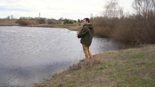 En man står vid floden och fiskar — Stockvideo