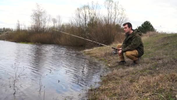 Samec rybáře stojí u řeky a chytá ryby — Stock video