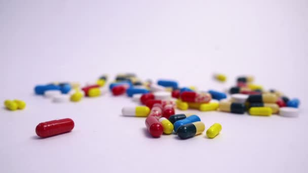 Muchas píldoras multicolores que yacen sobre un fondo blanco — Vídeos de Stock