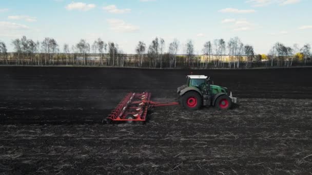 Toprağı sürerek tahıl eken bir traktörün yan görüntüsü. hava atışı. — Stok video