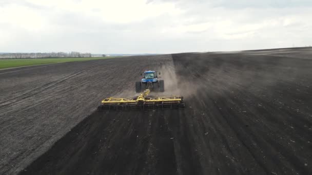 Ein großer, mächtiger blauer Traktor pflügt den Boden. — Stockvideo