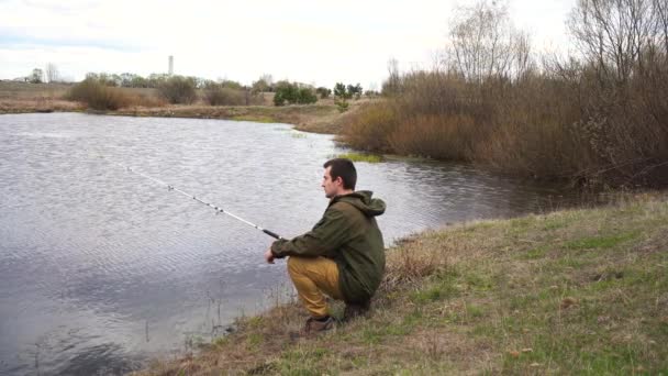 Squatting muž rybaření u řeky — Stock video