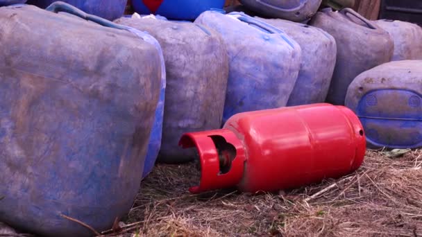 Red propane cylinder lies blue near canisters with fuel — Stock Video