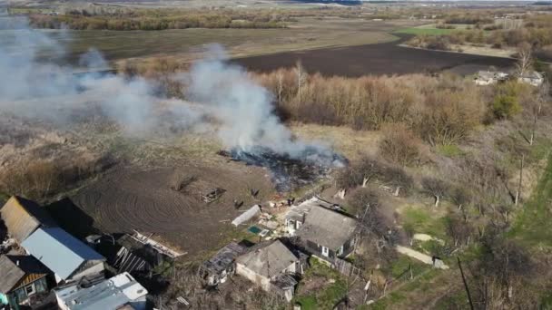 Burning grass and debris near residential buildings. aerial shooting. — Stockvideo