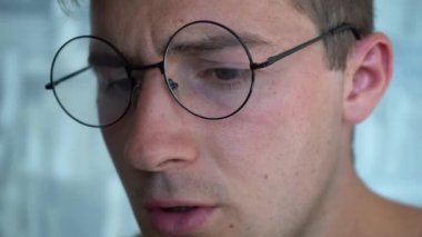 Bilgisayarda çalışan gözlüklü endişeli bir adam.