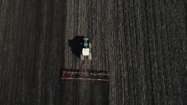 Drone movement over a large green tractor plowing the ground. aerial shooting — Vídeo de Stock