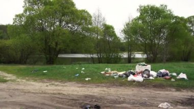 a large pile of rubbish on the green grass near the river bank