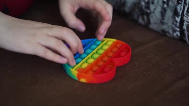 Niño jugando con juguete pop es simple hoyuelo primer plano corazón en forma de sofá — Vídeos de Stock