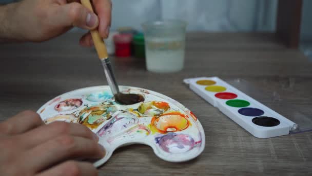 Un homme remuant la peinture avec un pinceau dans une palette spéciale — Video