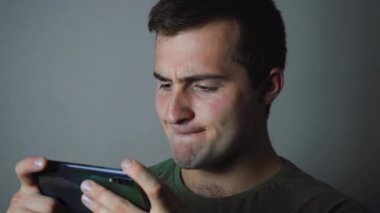 Adam odada otururken telefonda oynuyor.