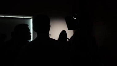 Karanlık bir odada usta bir sınıftaki fotoğrafçıların siluetleri.