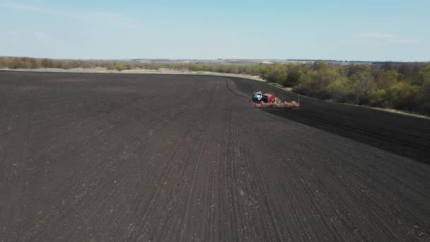 Een trekker ploegt de grond met een grote ploeg. luchtfoto 's — Stockvideo