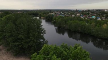 İnsansız hava aracı nehrin önündeki ağaçların üzerinden uçuyor. Hava görüntüsü 4k