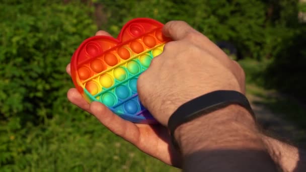 Hombre jugando con juguete pop es simple hoyuelo sentado en el parque — Vídeo de stock