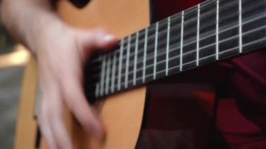 Adam sokakta otururken gitar çalıyor.