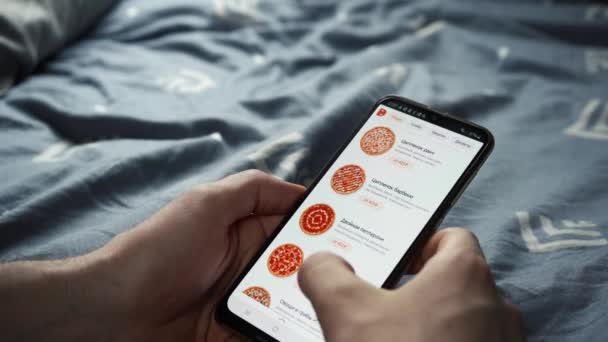 De man kiest pizza via de telefoon app. Moskou Rusland 29 maart 2021 — Stockvideo