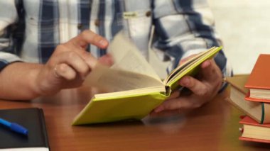 Adam kütüphanedeki masada bir kitabı karıştırıyor.