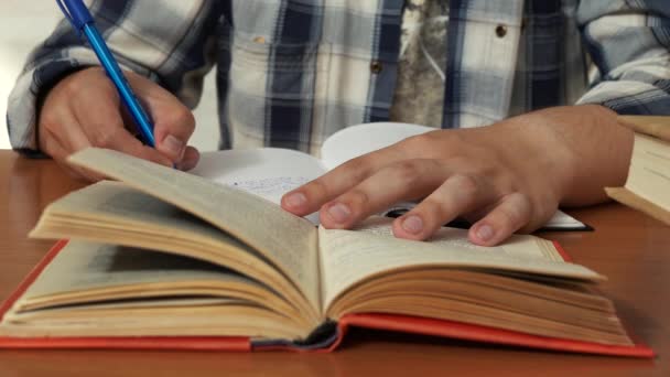 En man antecknar från en bok i en anteckningsbok — Stockvideo