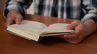Masada oturmuş kitap okuyan bir adam.