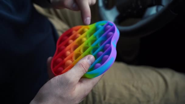 Muž hrající si s dětskou hračkou pop it simple dimple sitting in the car. — Stock video
